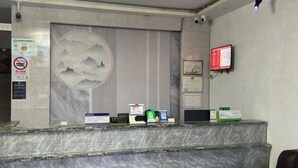 A reception desk with a marble top, a wall-mounted TV, and a large circular artwork depicting mountains. - Shanghai Longting Hotel (Shanghai)