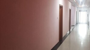 A long, narrow hallway with pink walls and a black baseboard, leading to a bright room at the end. - Shanghai Longting Hotel (Shanghai)