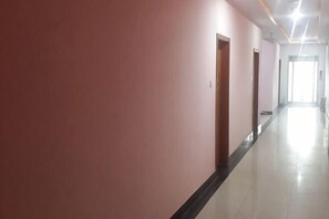 A long, narrow hallway with pink walls and a black baseboard, leading to a bright room at the end. - Shanghai Longting Hotel (Shanghai)