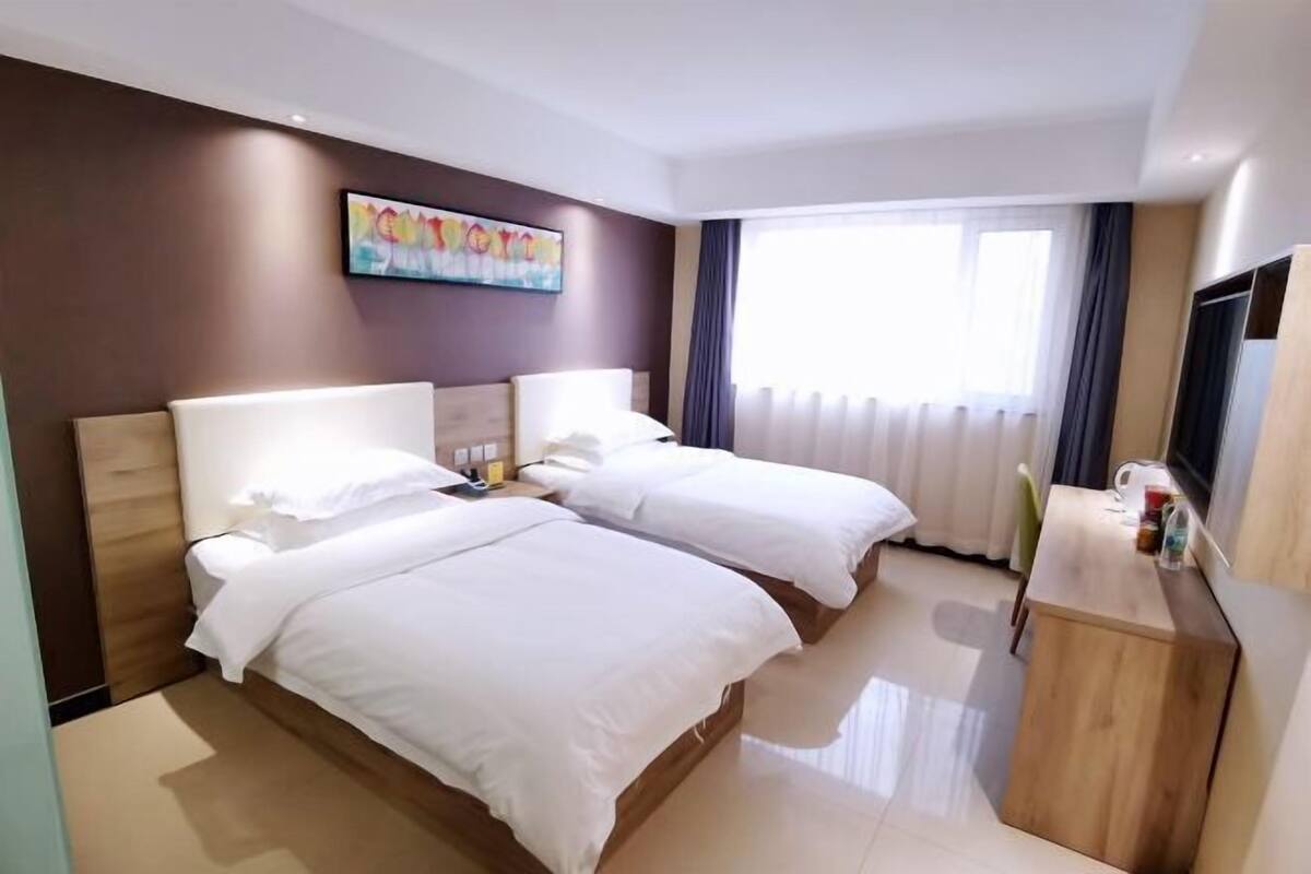 Een hotelkamer met twee bedden, een televisie, een bureau en een schilderij aan de muur.