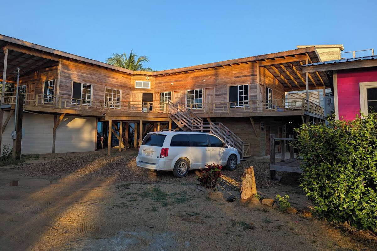 A two-story wooden house with a car parked in front.