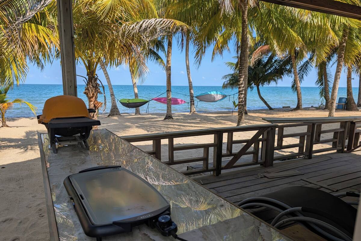 A beachside restaurant with a wooden deck, a grill, and a view of the ocean.