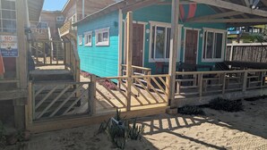 A wooden structure with a blue exterior, a wooden deck, and a sign warning of no lifeguard on duty. - CobiaBeach.com (Hopkins)
