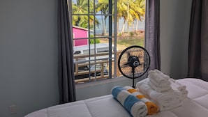 A hotel room with a bed, a window with curtains, a fan, and towels. - CobiaBeach.com (Hopkins)