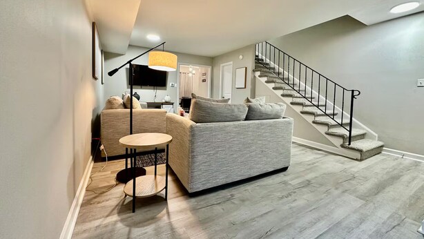 A modern living room with a grey sofa, a small round table, and a staircase leading to an upper floor.