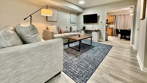 A modern living room with a sofa, coffee table, and a patterned rug.