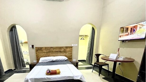 Ein Hotelzimmer mit einem Bett, einem kleinen Tisch mit Stuhl und einem Fernseher an der Wand.