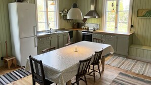 A kitchen with a dining table, chairs, a refrigerator, and a stove. - Summer house with secluded location in Julita   SE14028 (Julita)