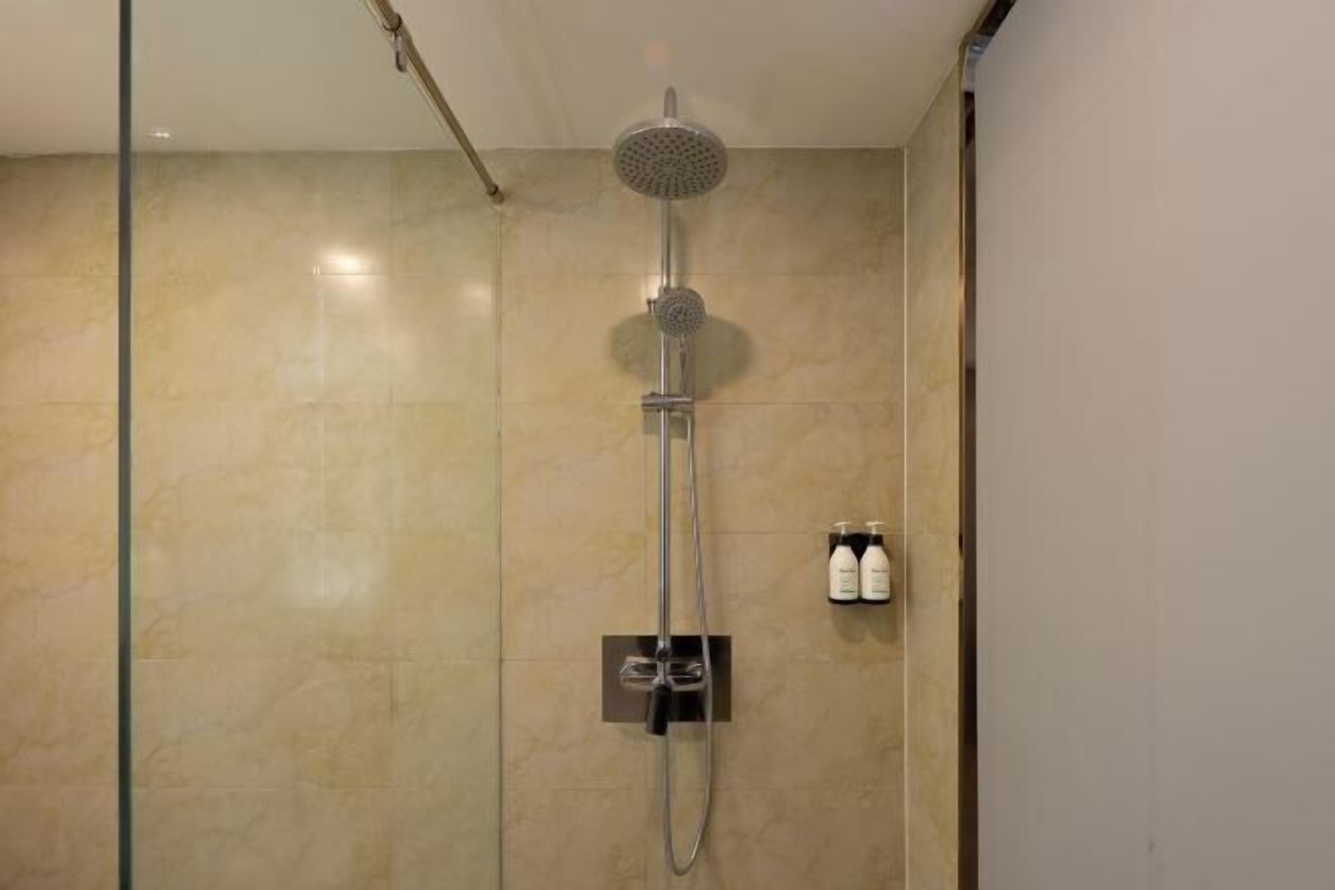 A shower with a handheld showerhead and a wall-mounted control panel.