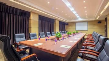 Una sala de conferències amb una taula llarga, diverses cadires i una pantalla de projector.