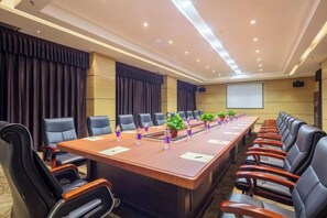 Une salle de conférence équipée d’une longue table, de nombreuses chaises et d’un écran de projection.