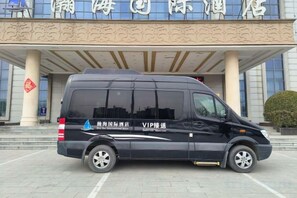 Een zwarte bestelwagen geparkeerd voor een gebouw met een bord waarop 'International Hotel' staat.