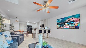 A modern living room with a sofa, coffee table, and a TV displaying a movie. - Elgin Oasis Suite B (Elgin)
