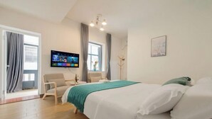 Habitación de hotel con cama, televisión, una silla, ventana con cortinas y un cuadro en la pared.