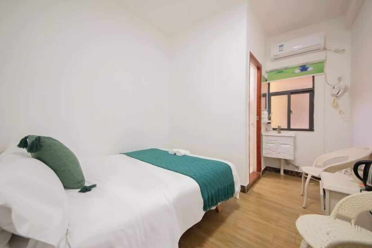 A small, clean room with a bed, a desk, and a chair.