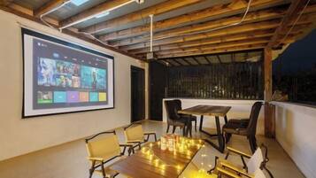 Relax in this cozy space with a wooden ceiling and comfortable seating area featuring a large screen displaying a variety of images.