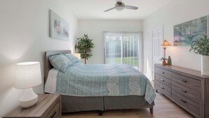 A bedroom with a bed, a nightstand, a dresser, a ceiling fan, a window with blinds, and a door. - Luxury upgraded, high ceiling home near Domain, high tech corrida, businesses. (Austin)