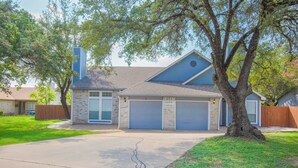 A two-story house with a garage, a large tree in front, and a well-maintained lawn. - Luxury upgraded, high ceiling home near Domain, high tech corrida, businesses. (Austin)