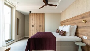 A modern bedroom with a bed, a wooden wardrobe, a ceiling fan, and a window. - 3-bedroom Holiday Home in Den Haag (The Hague)