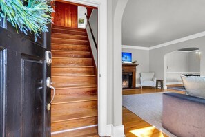 A staircase leading to a living area with a fireplace, a television, and a sofa.