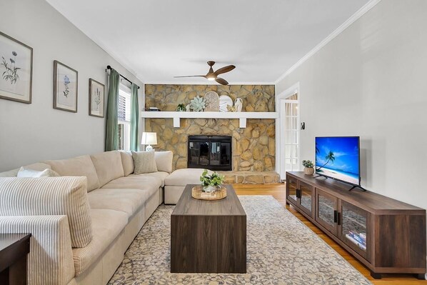 A living room with a stone fireplace, a sofa, a coffee table, and a television.
