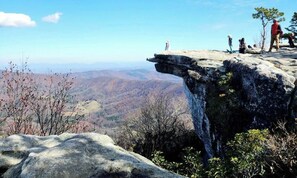 A rocky cliff with a panoramic view of a mountainous landscape.
