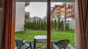 A view from a balcony with a table and chairs, overlooking a grassy area with trees and a building with balconies in the background. - 40m from ski slopes, fitness, swimming pool, sauna, tv, ski locker, 41m², Les Orres (Les Orres)