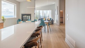 A modern kitchen with a large island, wooden chairs, and a view of the mountains. - Brand new, full duplex sleeps 22 - hot tub, laundry, sauna, BBQ w/ views (Silver Star Mountain)