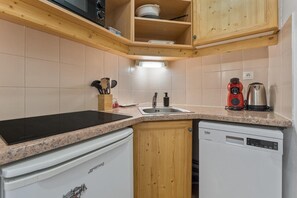 A compact kitchen with a granite countertop, a dishwasher, a coffee maker, and wooden cabinets.