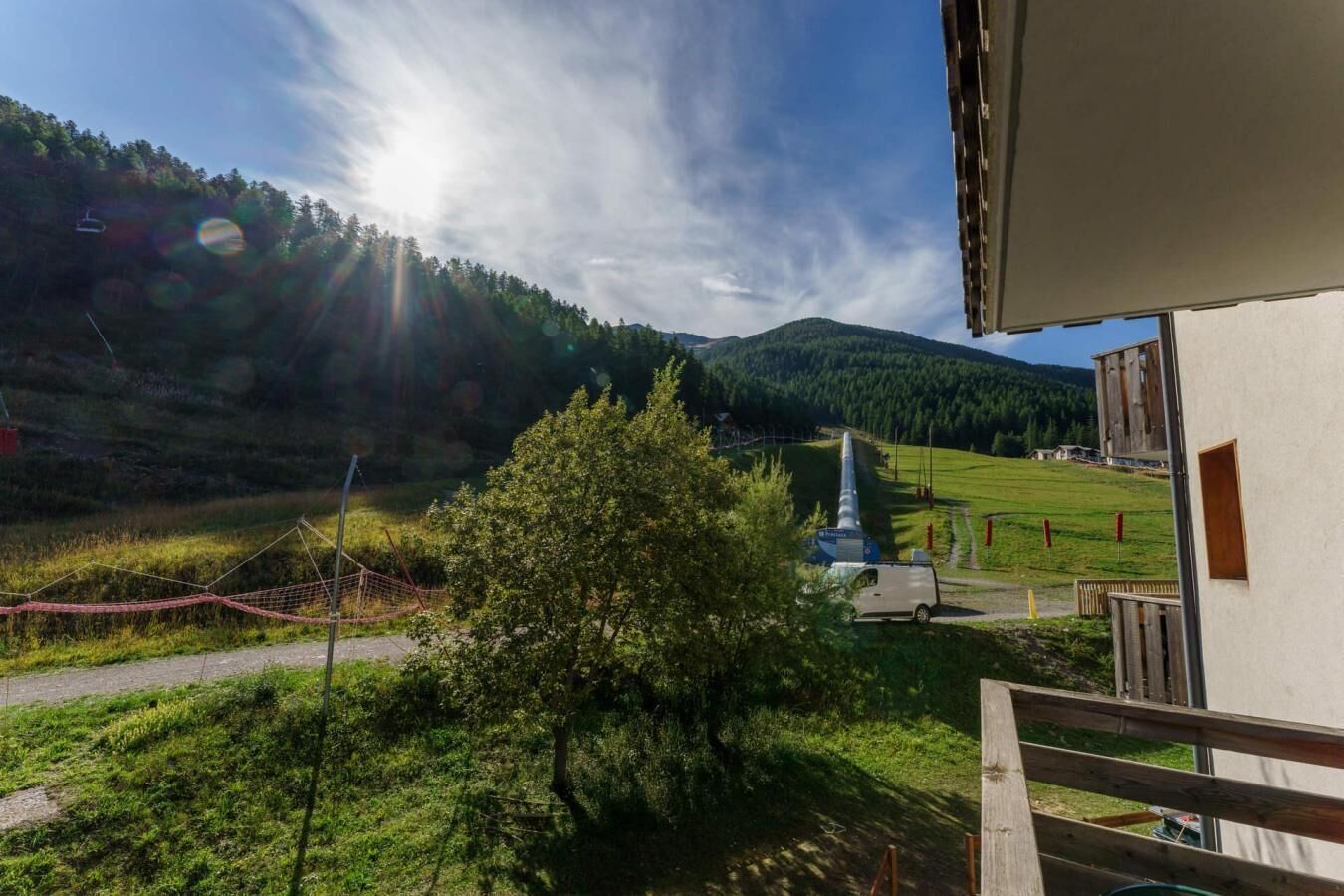 A view from a balcony overlooking a rural landscape with a church and a hill in the distance.