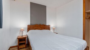 Une chambre à coucher avec une tête de lit en bois, un couvre-lit blanc, deux tables de chevet avec des lampes et un plancher en bois.