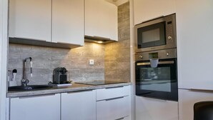 A modern kitchen with white cabinets, a built-in microwave, and an oven.