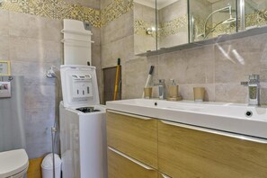 A bathroom with a white sink, wooden cabinets, a mirror, and a shower area.