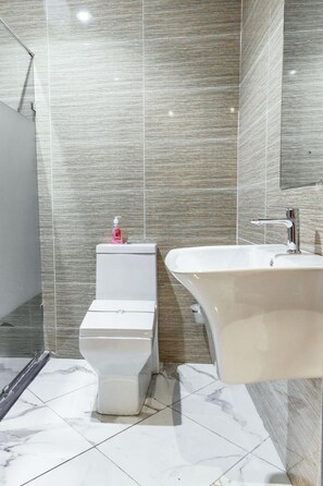 Een moderne badkamer met toilet, wastafel en douche.