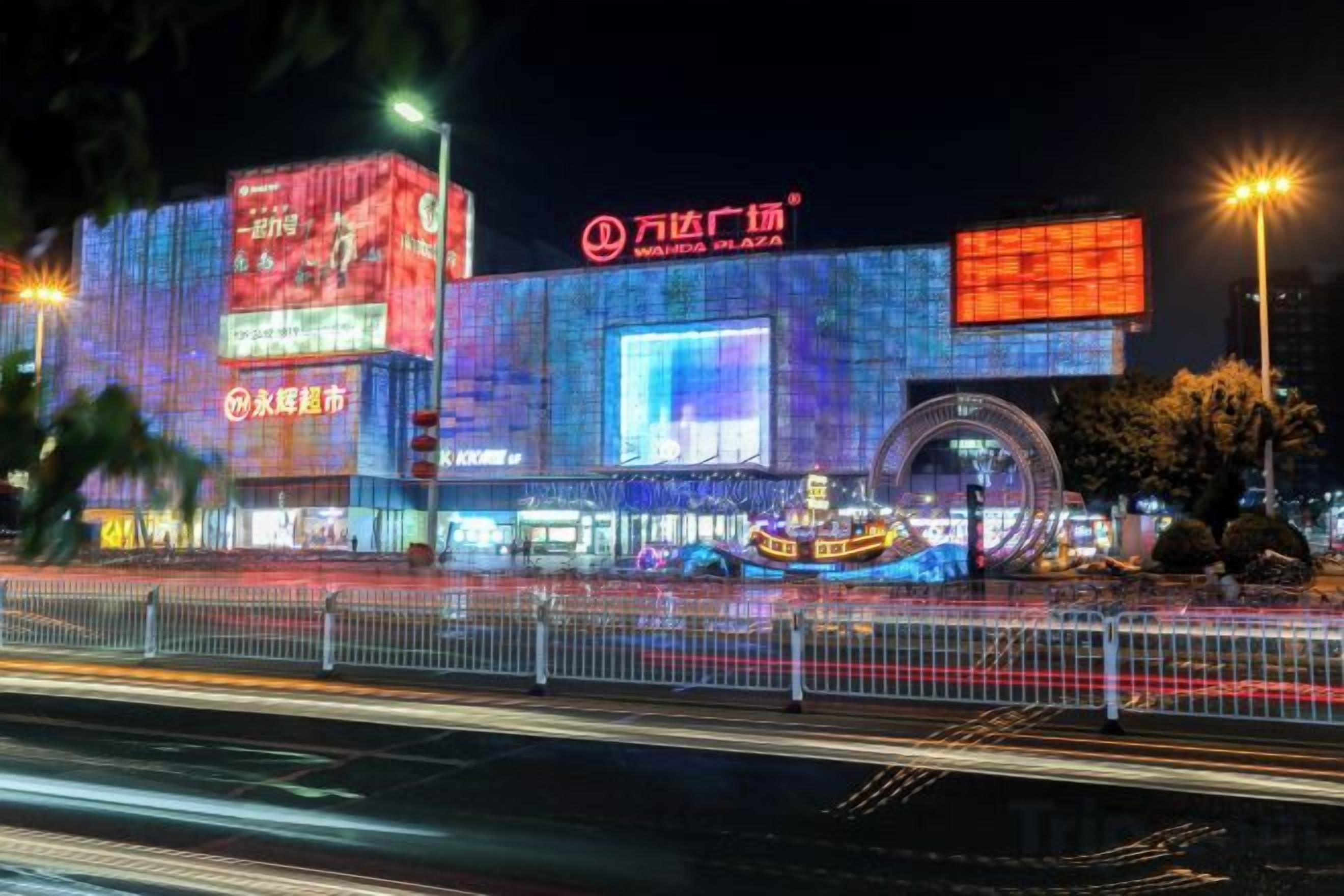 A brightly lit building with illuminated signage and a large circular structure in front.
