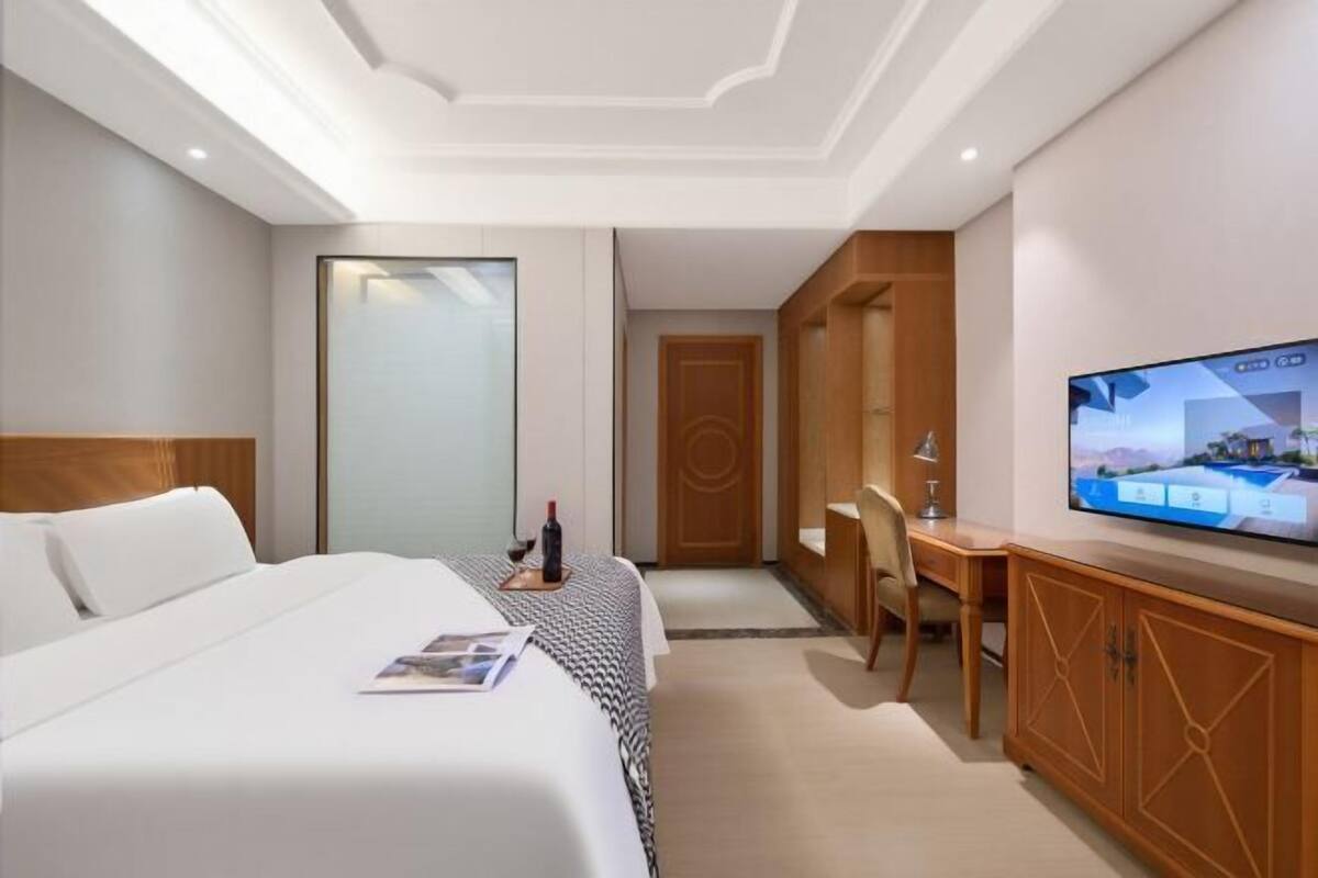 Hotellihuone, jossa on sänky, työpöytä, televisio ja vaatekaappi.