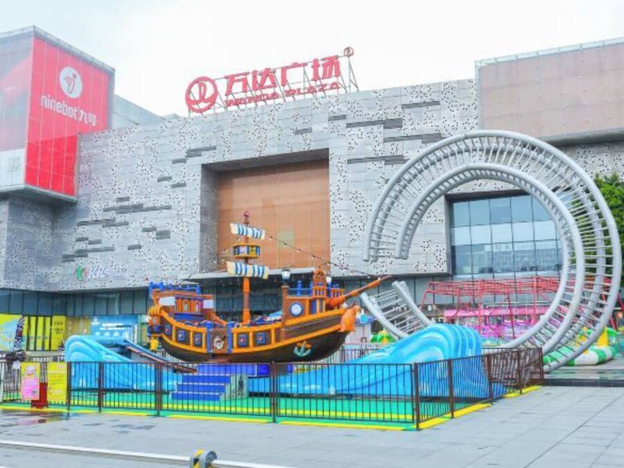 A modern building with a large circular structure in front, a sign for 'NineBot', and a colorful ship decoration.