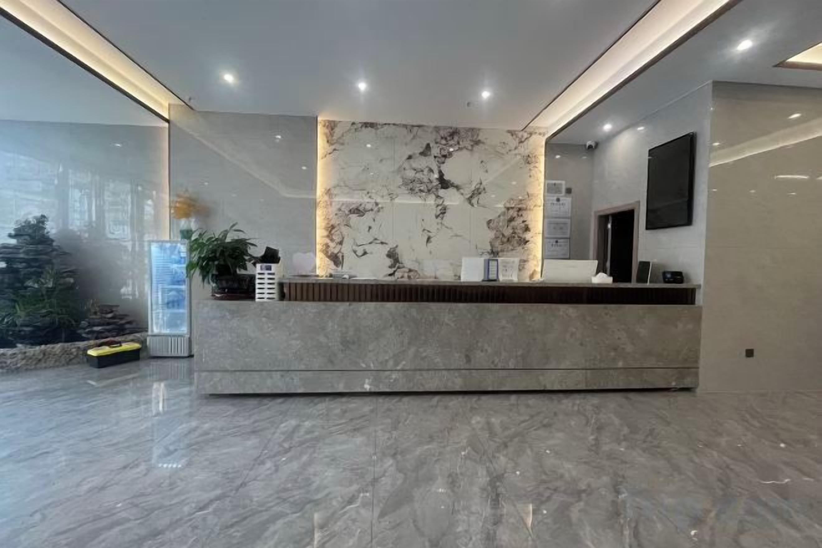 A reception area with a marble counter, a plant, and a large window.
