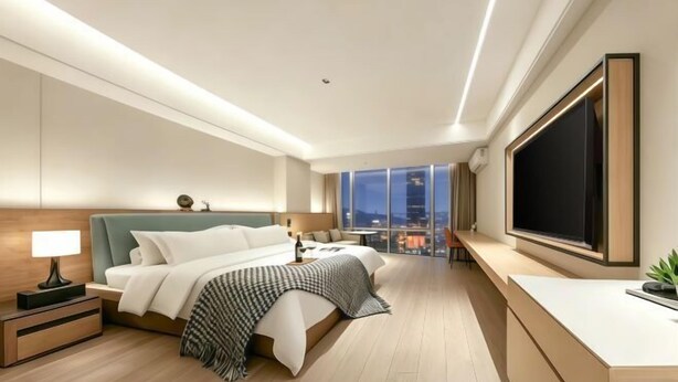 Una habitación de hotel moderna con una cama grande, mesitas de noche, un escritorio y un ventanal con vistas a la ciudad.