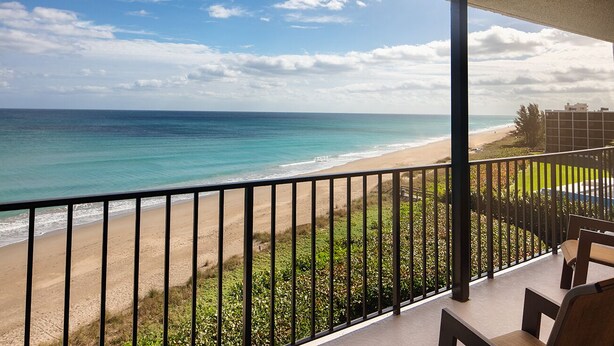 Un balcon avec vue sur une plage et l’océan.