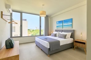 A bedroom with a bed, a bedside table, a hanging light, a window, and a painting on the wall.
