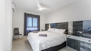 Un dormitorio moderno con cama, una silla, un escritorio y un ventilador de techo.
