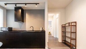 A modern kitchen with dark cabinetry, a black range hood, and a built-in microwave. - Saint Margaret Apartments (Cagliari)