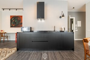 A modern kitchen with a central island, stainless steel appliances, and a pendant light.