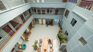 A multi-level atrium with a central seating area, balconies, and potted plants. - Yinlilai Business Hotel (Tianquan Hospital of Traditional Chinese Medicine Branch) (Tianquan)