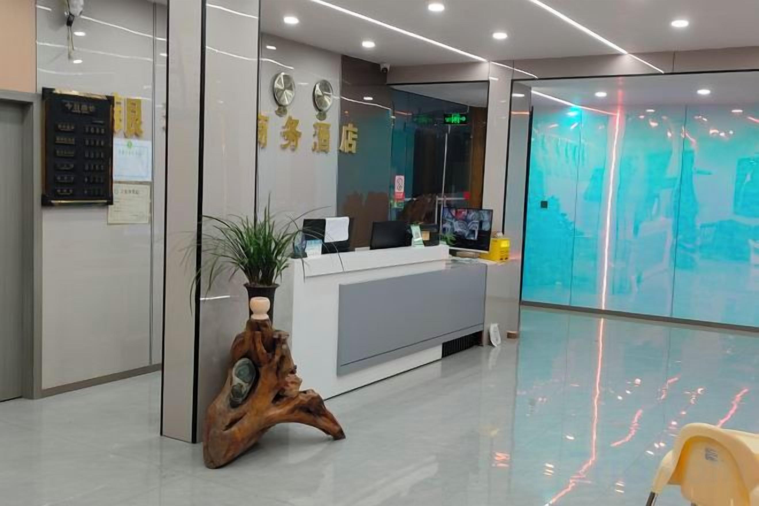 Una zona de recepción con un mostrador, una planta y un reloj en la pared.