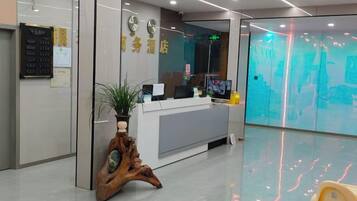 A reception area with a desk, a plant, and a wall-mounted clock.