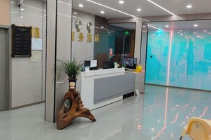 Una zona de recepción con un mostrador, una planta y un reloj en la pared.