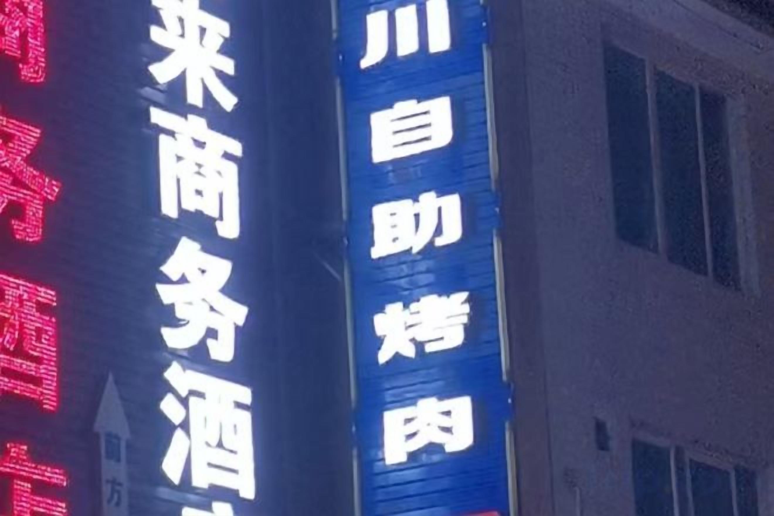 A building with illuminated signage in a foreign language, likely indicating a business or commercial establishment.