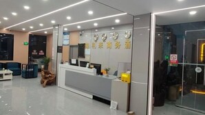 A modern reception area with a reception desk, seating area, and a glass door entrance. - Yinlilai Business Hotel (Tianquan Hospital of Traditional Chinese Medicine Branch) (Tianquan)